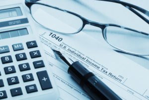 Glasses, calculator, 1040 tax form and a fountain pen