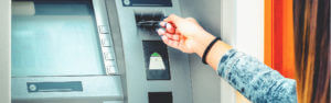 Young woman inserting her card into the ATM