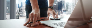 Professional standing at their desk with their mobile phone and laptop