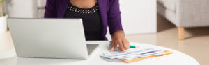 Woman with a laptop with paper checks in front of her