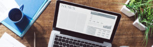 Coffee mug and laptop with the morning news on the computer screen