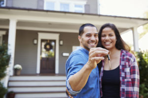 Portrait Of Couple Holding Keys To New Home On Moving In Day