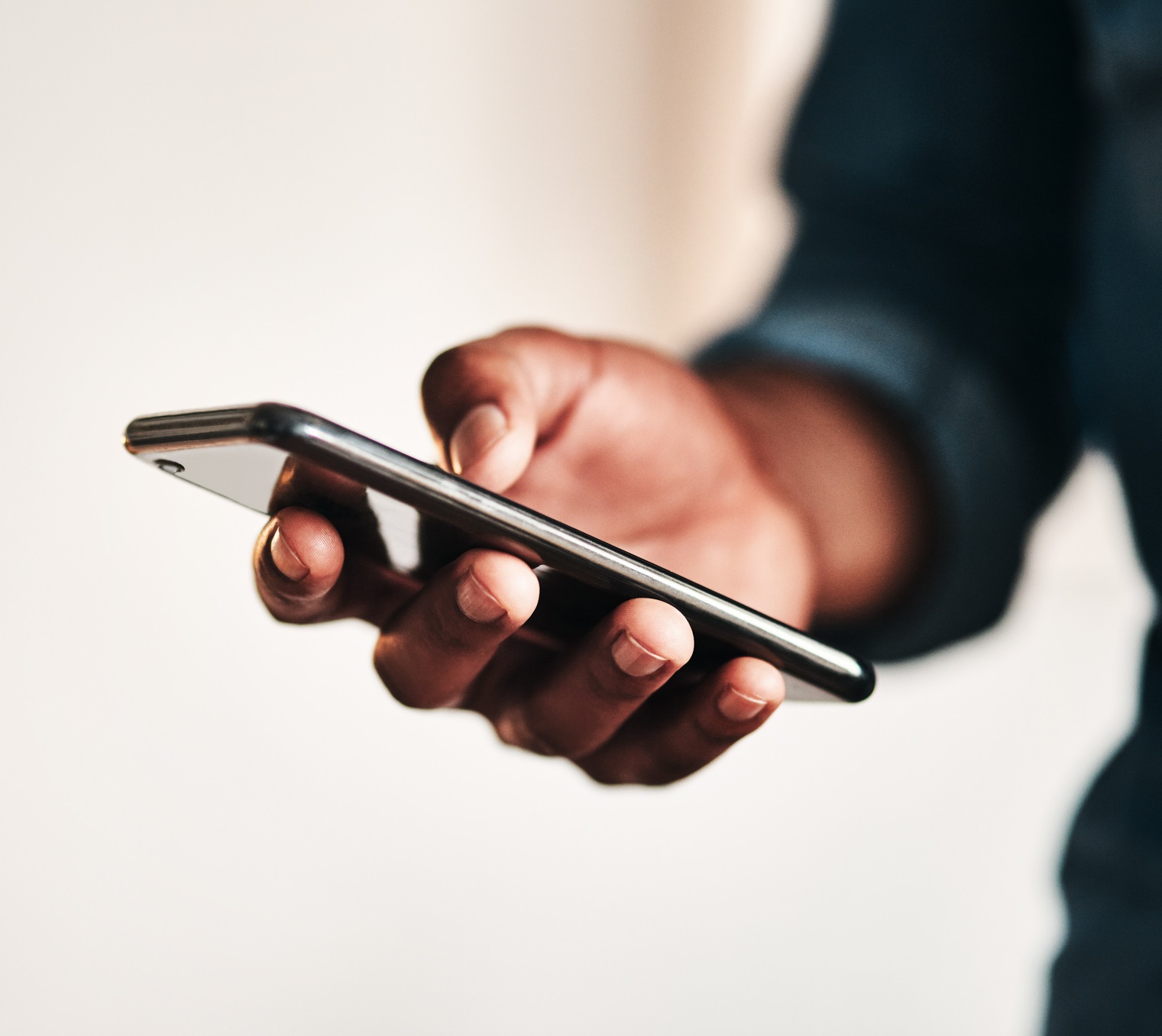 Cropped shot of an unrecognizable businessman standing alone in his home office and texting on his cellphone