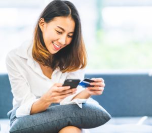 Young female looking at phone and checking card