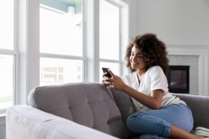 Woman using mobile device on couch at home