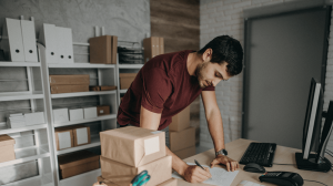 Man working on paperwork while processing and sending out boxes