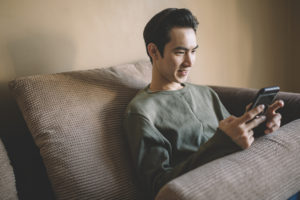 A man sitting on his couch using his phone