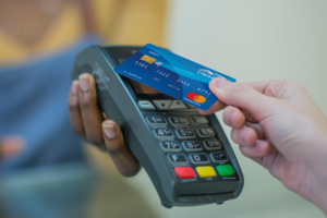 Blue UNCLE Debit Card being held over a reader at checkout