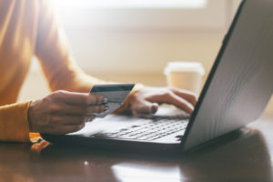 Hands holding credit card and coffee to go.