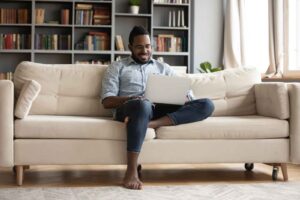 African American man rest on sofa using notebook