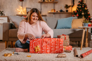 Woman wrapping Christmas gifts at home.