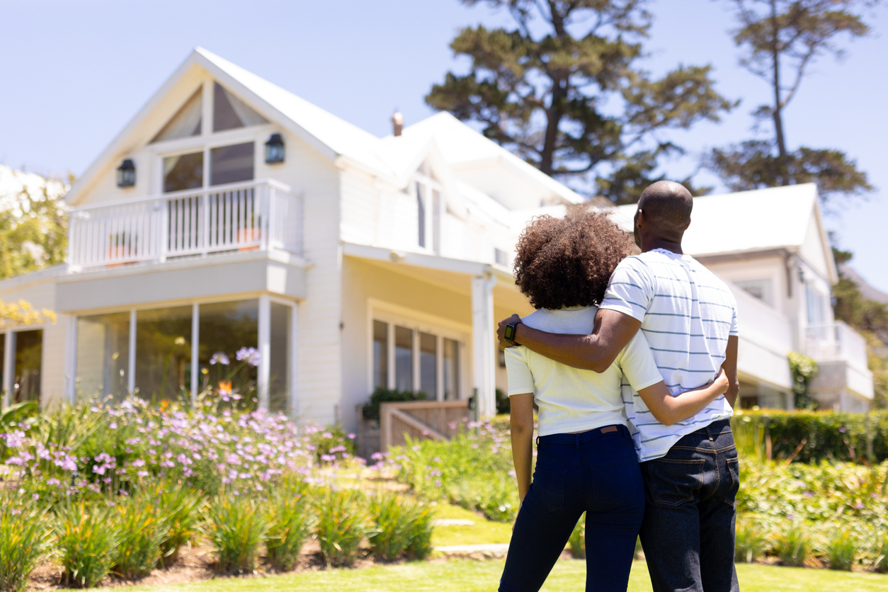 Young couple standing in the garden in front of their home