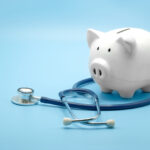 Piggy Bank With Stethoscope Isolated On Light Blue Background With Copy Space. Health Care Financial Checkup Or Saving For Medical Insurance Costs Concept.