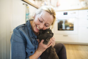 Beautiful senior woman in denim shirt with her cat at home, relaxing