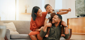 A happy mixed race family of three relaxing in the lounge and being playful together. Loving black family bonding with their son while playing fun games on the sofa at home