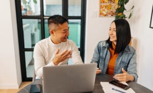 Smiling couple using laptop and talking to each other