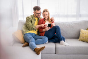Young couple surfing the net on mobile phone at home.