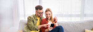 Young couple surfing the net on mobile phone at home.