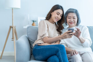 Asian lovely family, daughter use mobile phone with older mother.