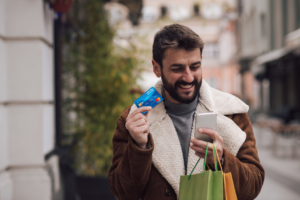 Man holding debit card and shopping bags while smiling