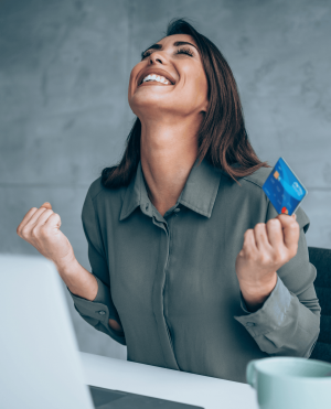 Woman excited while holding debit card at office.