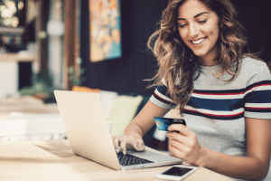Smiling woman with credit card and laptop.