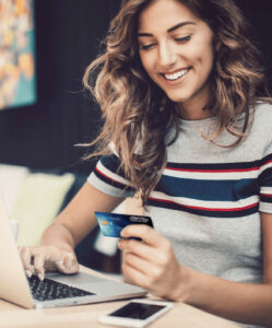 Smiling woman with laptop and credit card.
