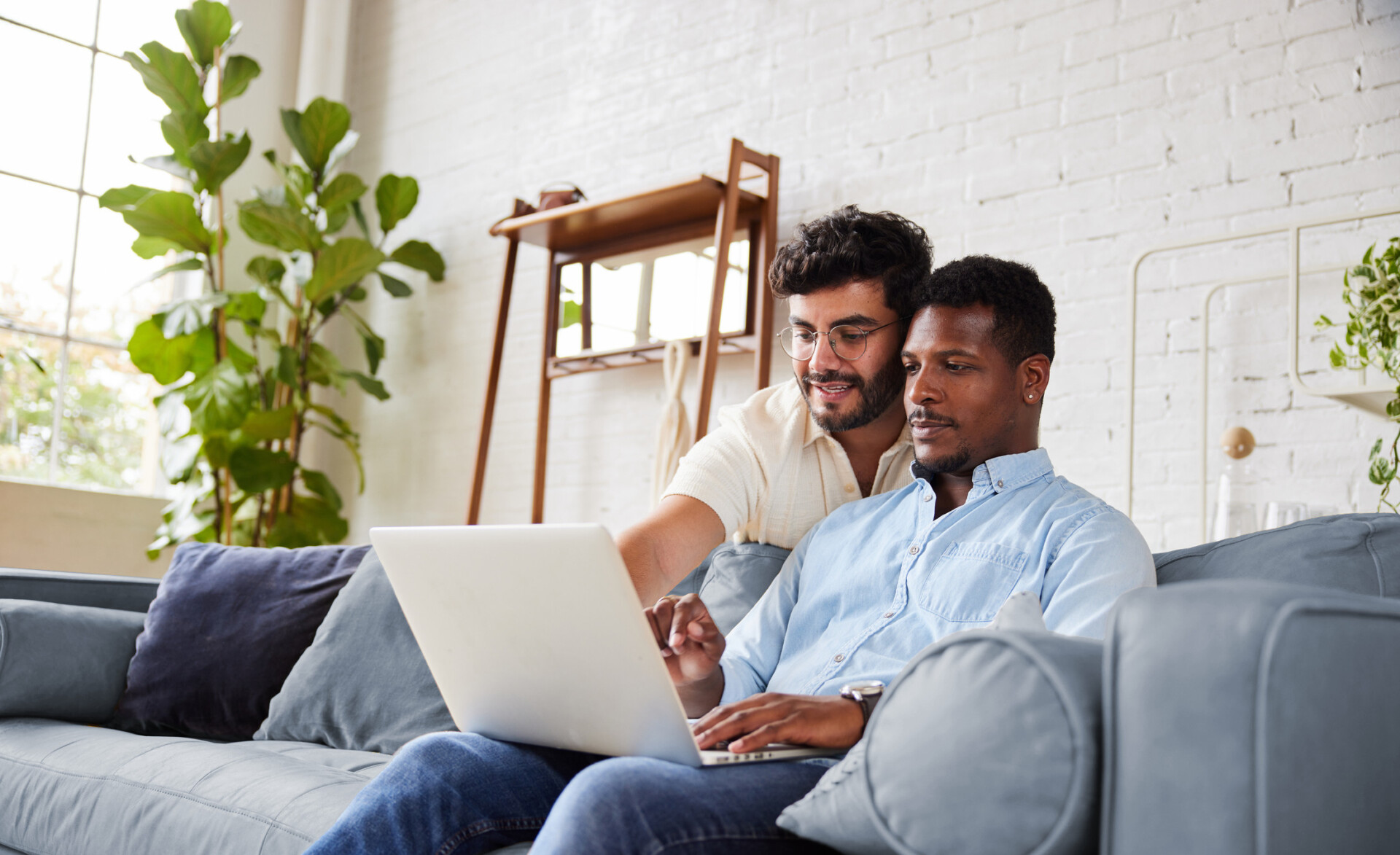 Couple looking at laptop from couch at home.