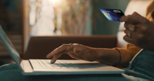 Person holding their credit card and using laptop.
