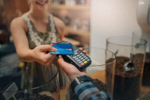 Woman Making Payment With Debit Card Using Handheld Device