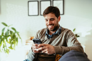 Smiling man using smartphone at home