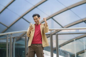 Happy Man Excitedly Looking At His Phone In A Public Building
