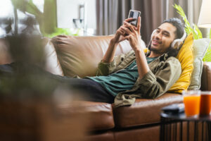 Man In Headphones Listening To The Music And Gesturing While Sitting On His Couch