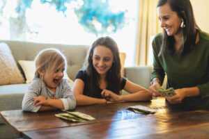 Millennial Female Mother With Teenage And Pre School Age Daughters Handling Money