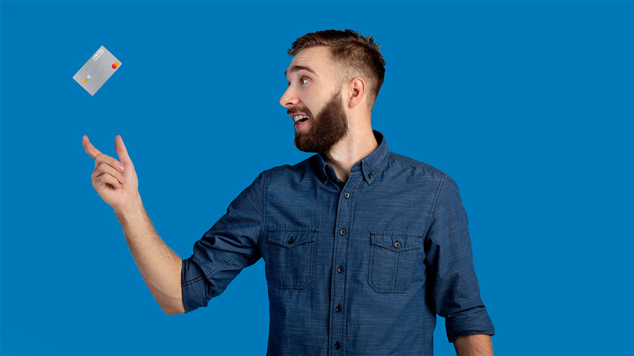 Smiling man catching a credit card falling into his hand