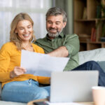 Family Insurance Concept. Happy Middle Aged Couple Reading Documents At Home