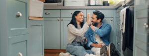Couple high fiving while sitting on kitchen floor