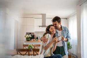 Young Couple Drinking Morning Coffee Enjoying The Weekend In Their New Apartment