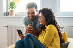 Smiling couple looking at phone at home