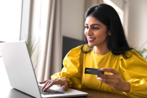 Woman holding UNCLE business banking credit card while on laptop