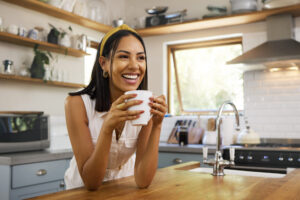 Happy Woman, Coffee Or Tea In Home Kitchen And Relax With A Smile In The Morning At House.