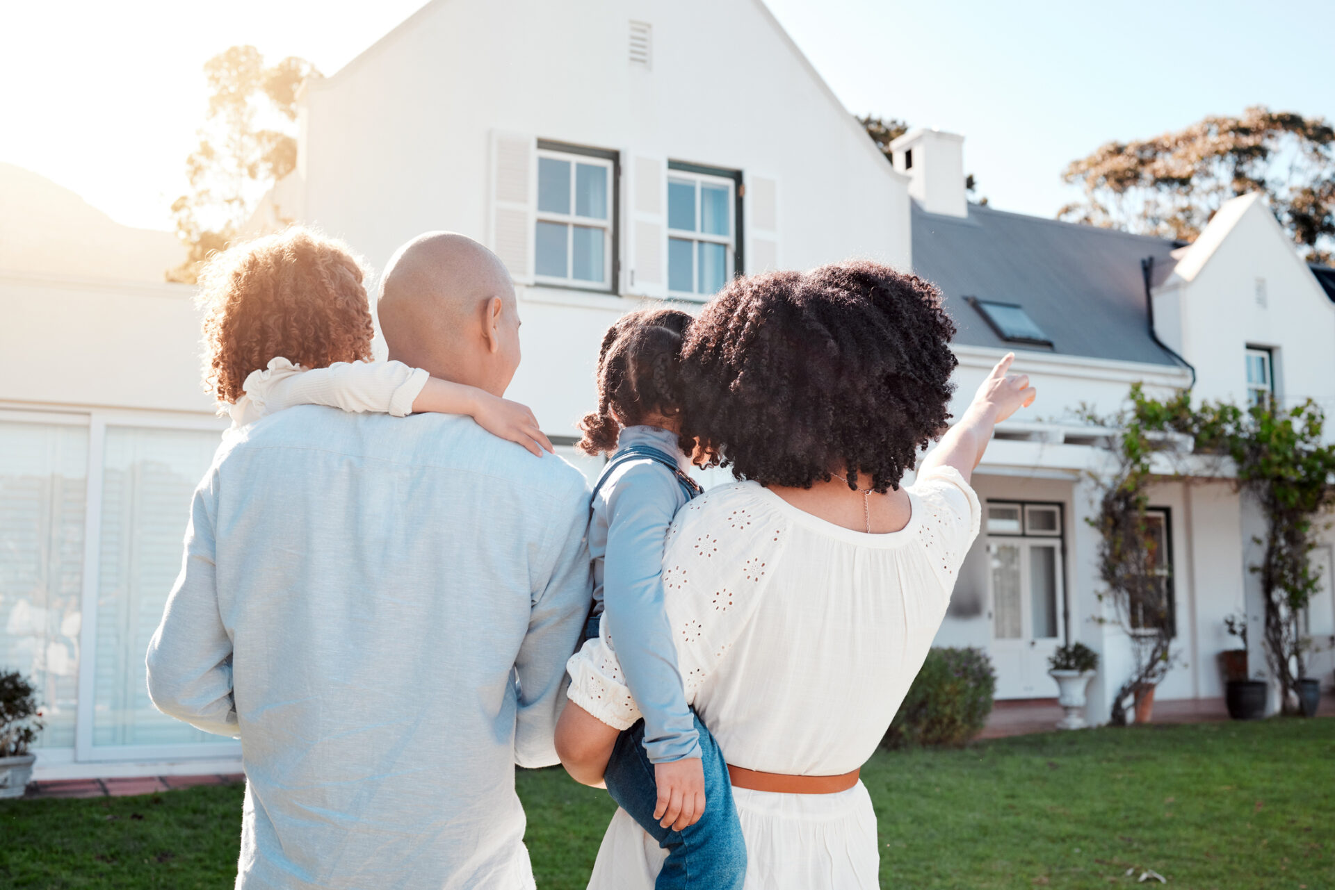 Real estate, love and family in the yard of their new house bonding and spending quality time together. Property and back of young mom, dad and children standing by their modern home