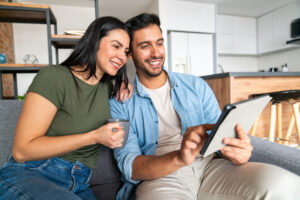 Happy couple at home using a digital tablet