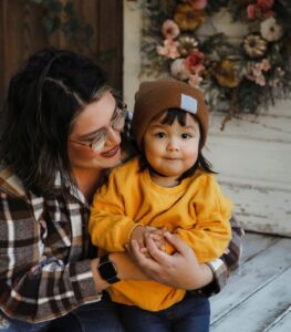 An image of a two~year~old girl and her mother, sitting on a porch.