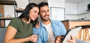 Happy couple at home using a digital tablet