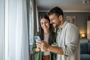 A couple drinks morning coffee and looks at phone together