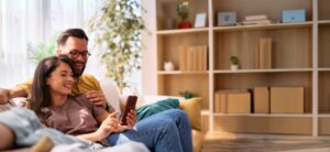 Couple using a mobile phone on the couch.