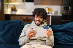 Man holding banking card and smartphone, making purchases or ordering online.