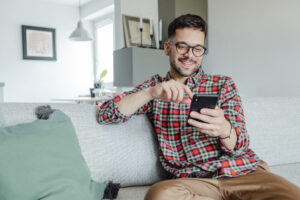 Smiling man using cell phone on couch