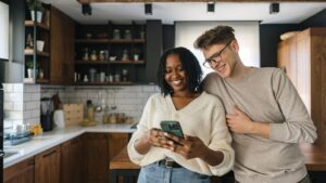 Couple using phone in kitchen.